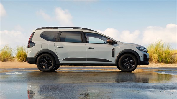 Dacia Jogger фотографиран од страна покрај водна површина со трева во позадина.