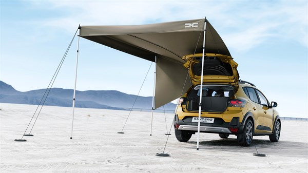 Dacia Sandero Stepway паркирана во пуст предел со подигната задна врата, со инсталирана кровна настрешница InNature за да се создаде засенчен надворешен простор.