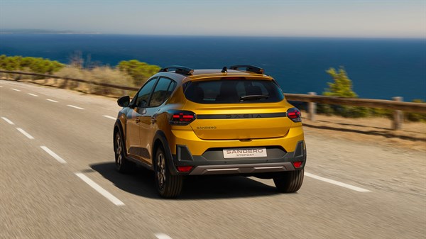 Dacia Sandero Stepway  фотографирано одназад, возејќи по крајбрежен пат, со поглед на морето во позадина.