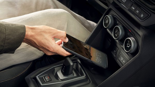 Раката на возачот го става мобилниот телефон на вградениот индуктивен безжичен полнач во Dacia Sandero Stepway.